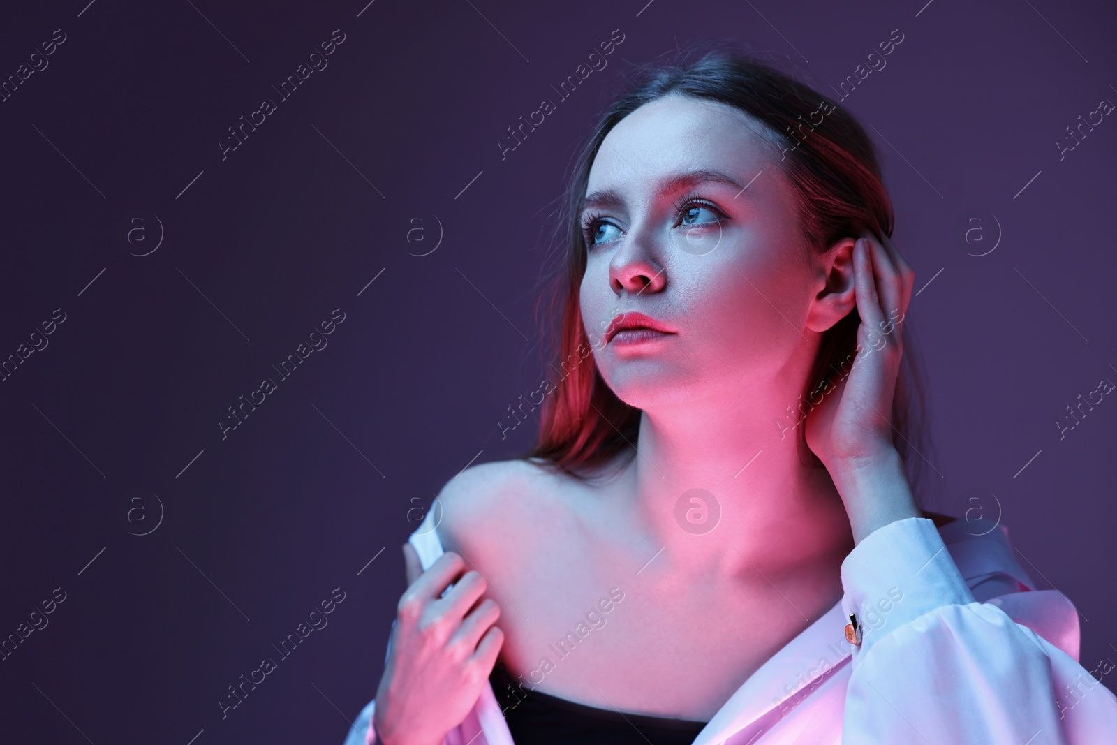 Photo of Fashionable portrait of beautiful young woman on purple background in neon lights