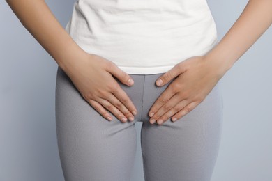 Woman suffering from herpes genital on grey background, closeup