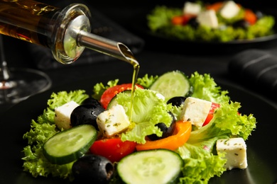 Photo of Dressing tasty fresh Greek salad with olive oil, closeup