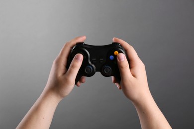 Photo of Woman using wireless game controller on grey background, closeup