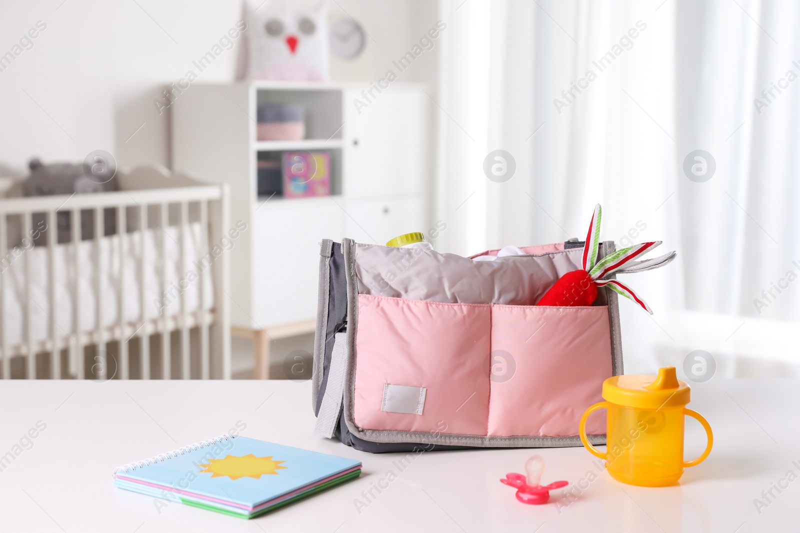 Photo of Maternity bag with baby accessories on table indoors. Space for text