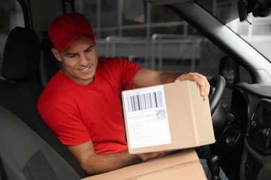 Photo of Courier in car with packages. Delivery service