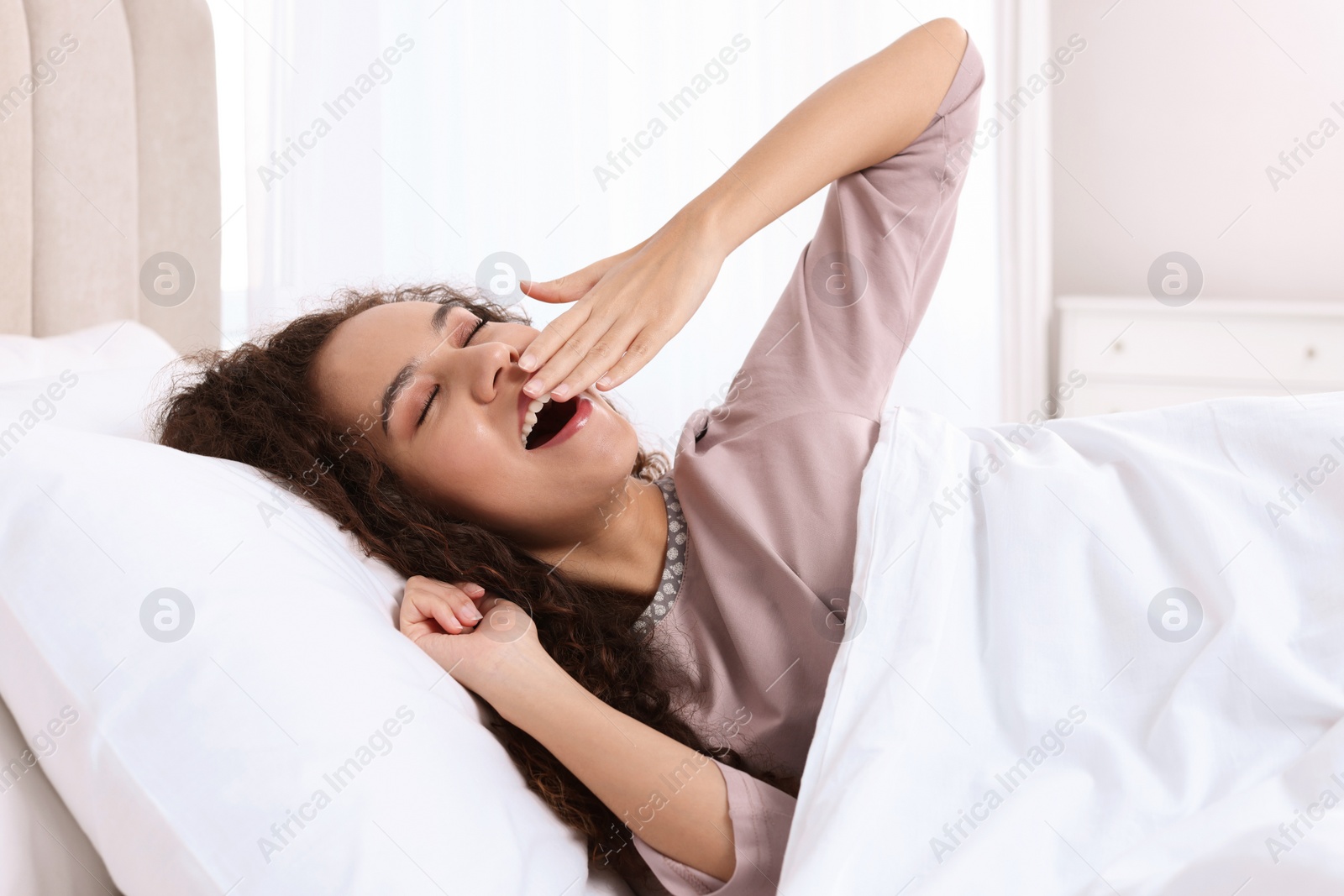 Photo of Happy African American woman awakening in bed at home