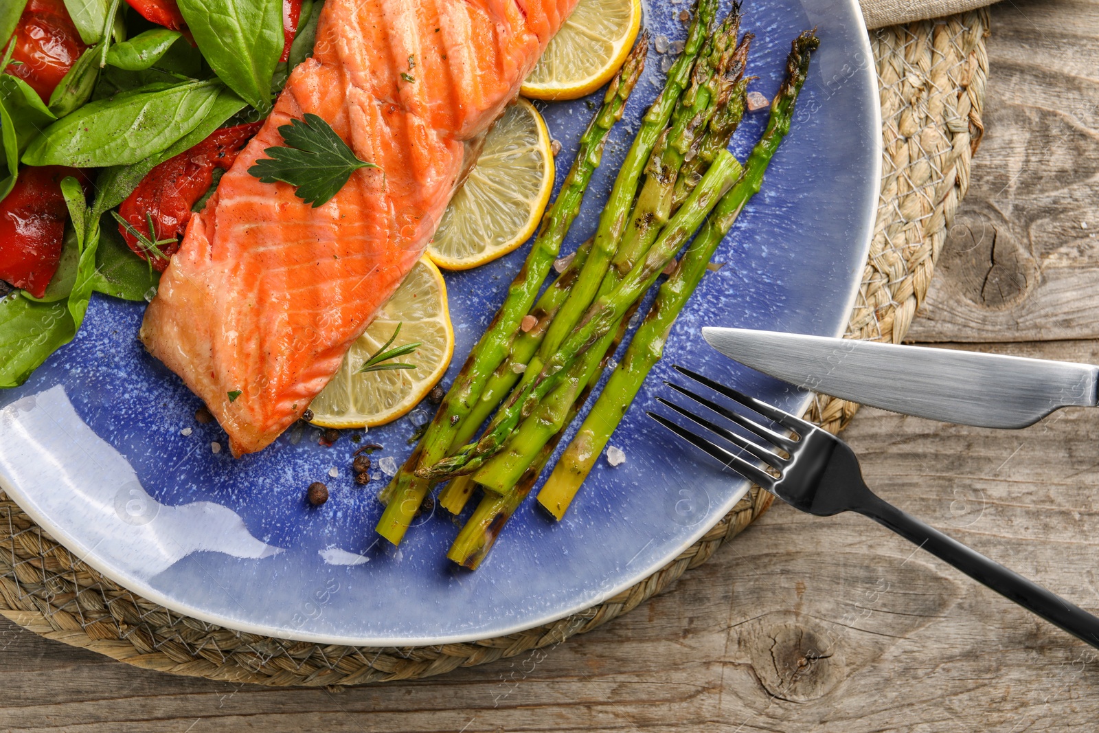 Photo of Tasty grilled salmon with tomatoes, asparagus, spinach and lemon served on table, top view