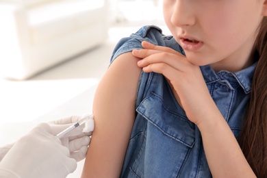 Doctor vaccinating little girl in hospital