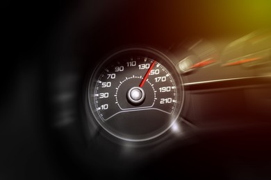 Image of Speedometer on car dashboard under yellow light, closeup. Motion blur effect