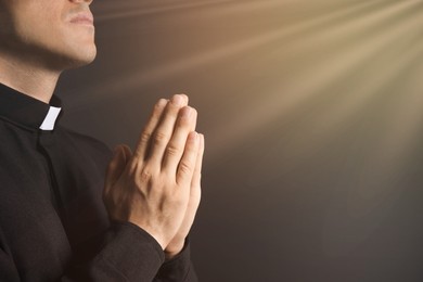 Image of Holy light and priest praying on black background, closeup. Space for text