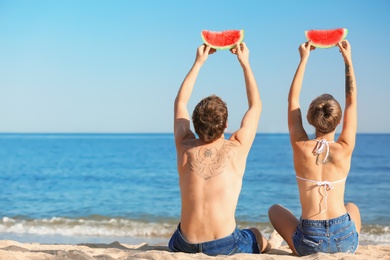 Photo of Young couple with watermelon slices on beach. Space for text