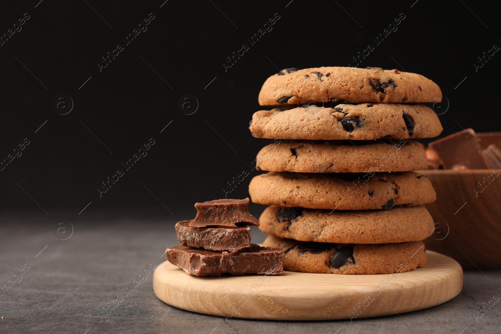 Photo of Stack of delicious chocolate chip cookies on grey table, closeup. Space for text