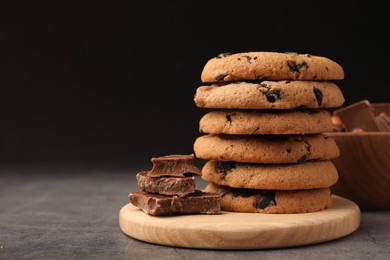 Photo of Stack of delicious chocolate chip cookies on grey table, closeup. Space for text