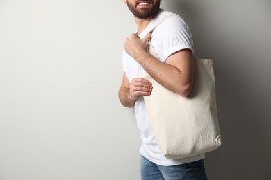 Happy man with eco bag on light background, closeup. Space for text