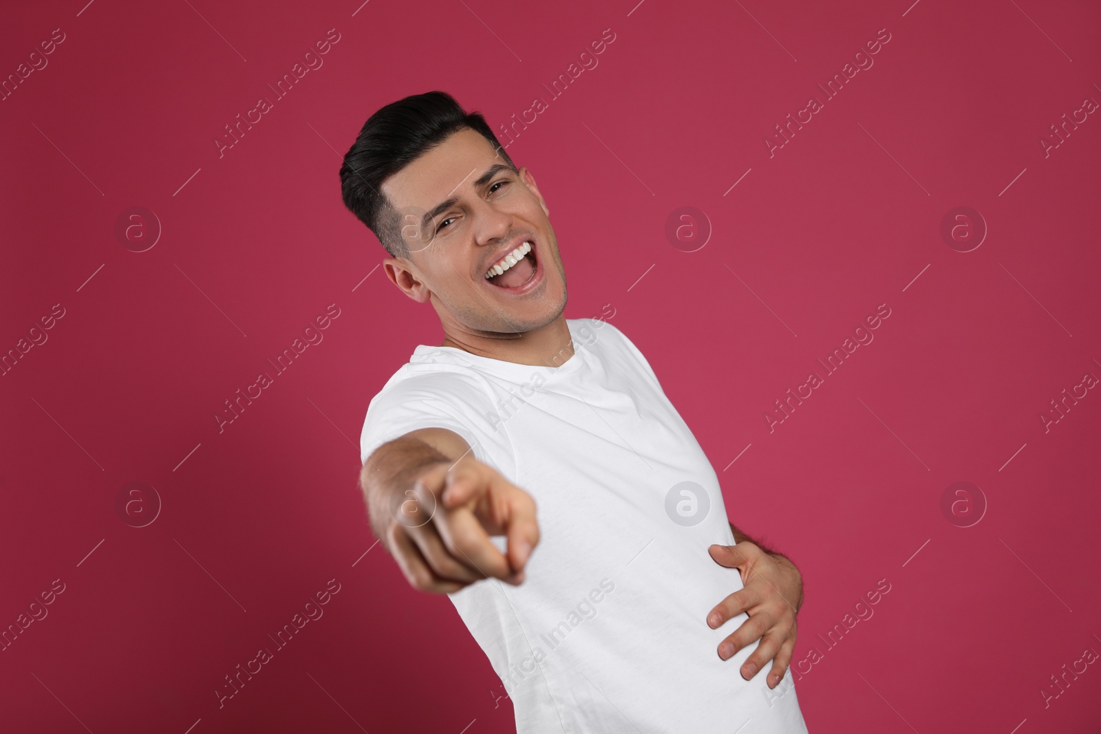 Photo of Handsome man laughing on maroon background. Funny joke