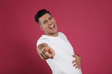 Photo of Handsome man laughing on maroon background. Funny joke