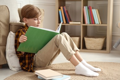 Little boy reading book on floor at home