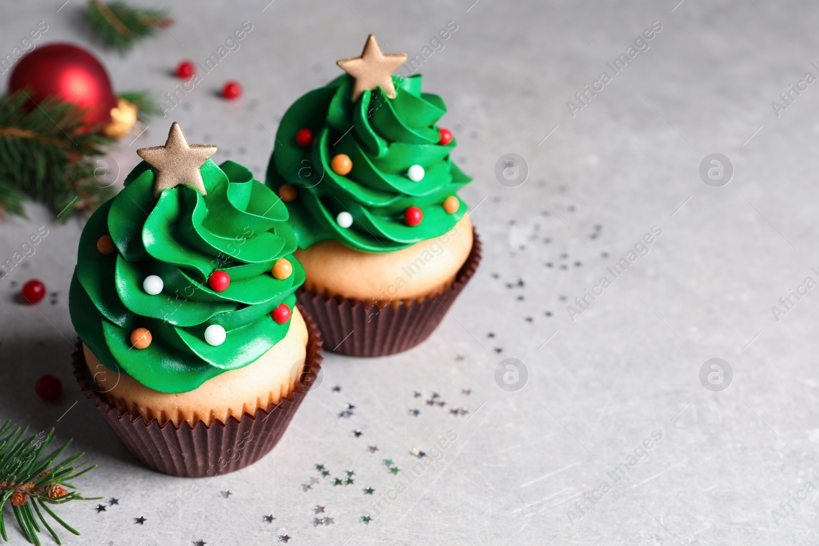 Photo of Christmas tree shaped cupcakes on light grey table. Space for text