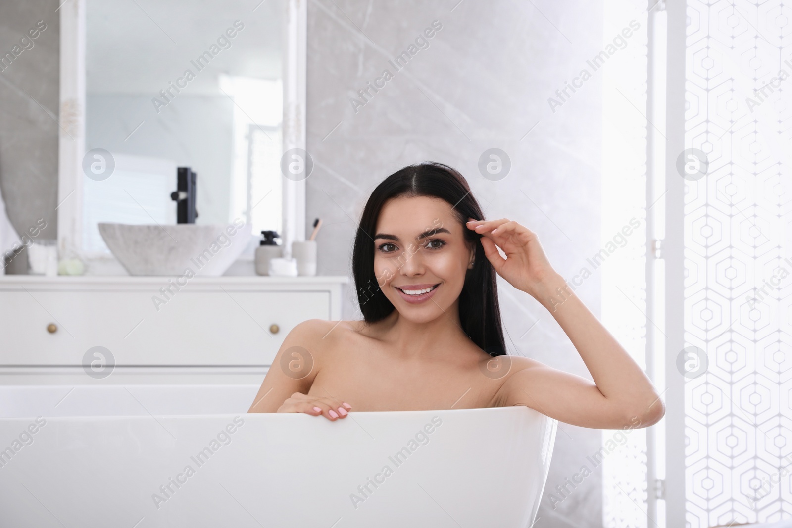 Photo of Beautiful young woman relaxing in bathtub at home