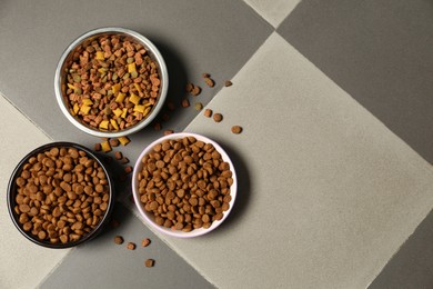 Photo of Pet bowls with dry food on floor, flat lay. Space for text