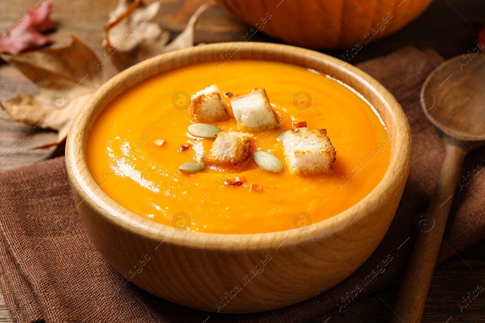 Photo of Bowl with tasty pumpkin cream soup on wooden table