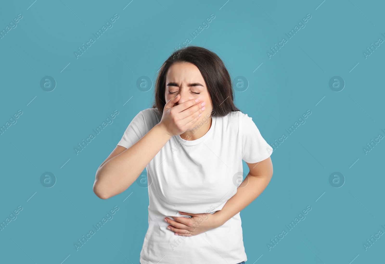 Photo of Young woman suffering from stomach ache and nausea on light blue background. Food poisoning