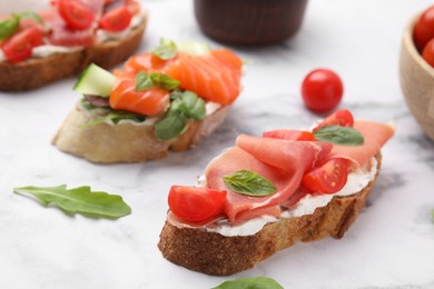 Photo of Different tasty bruschettas on white marble table, closeup