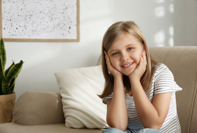 Photo of Cute little girl on couch at home. Space for text