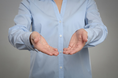 Photo of Woman holding something against grey background, focus on hands