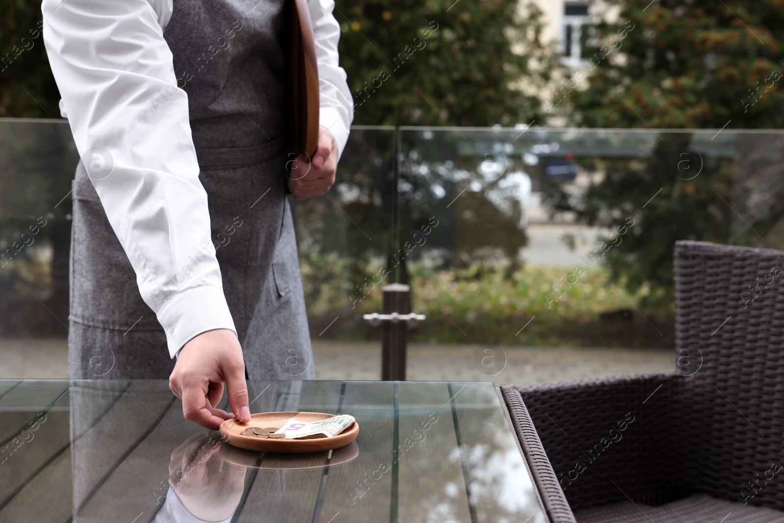 Photo of Waiter taking tips from wooden table in outdoor cafe, closeup