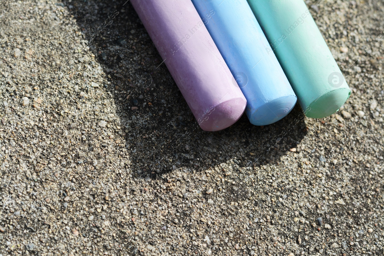 Photo of Colorful chalk sticks on asphalt, above view. Space for text