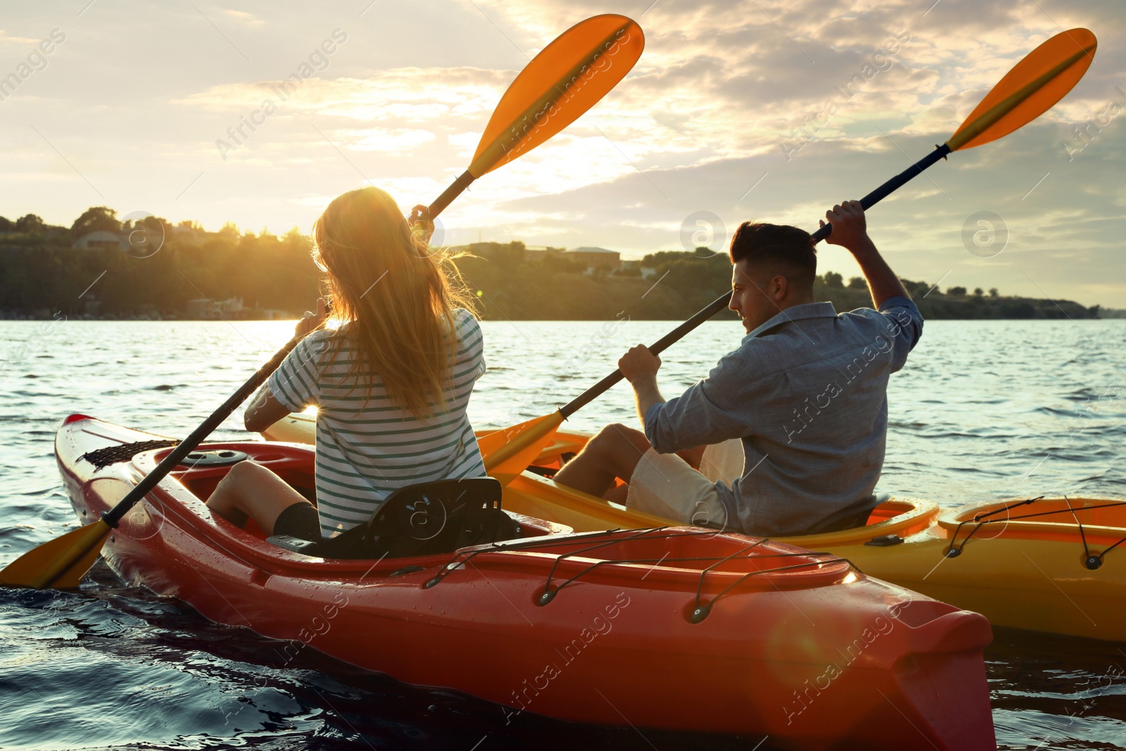 Photo of Couple kayaking on river at sunset, back view. Summer activity