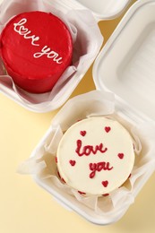 Bento cakes in takeaway boxes on beige table, flat lay. St. Valentine's day surprise