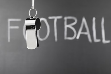 Photo of Referee whistle against chalkboard with word Football, closeup. Space for text