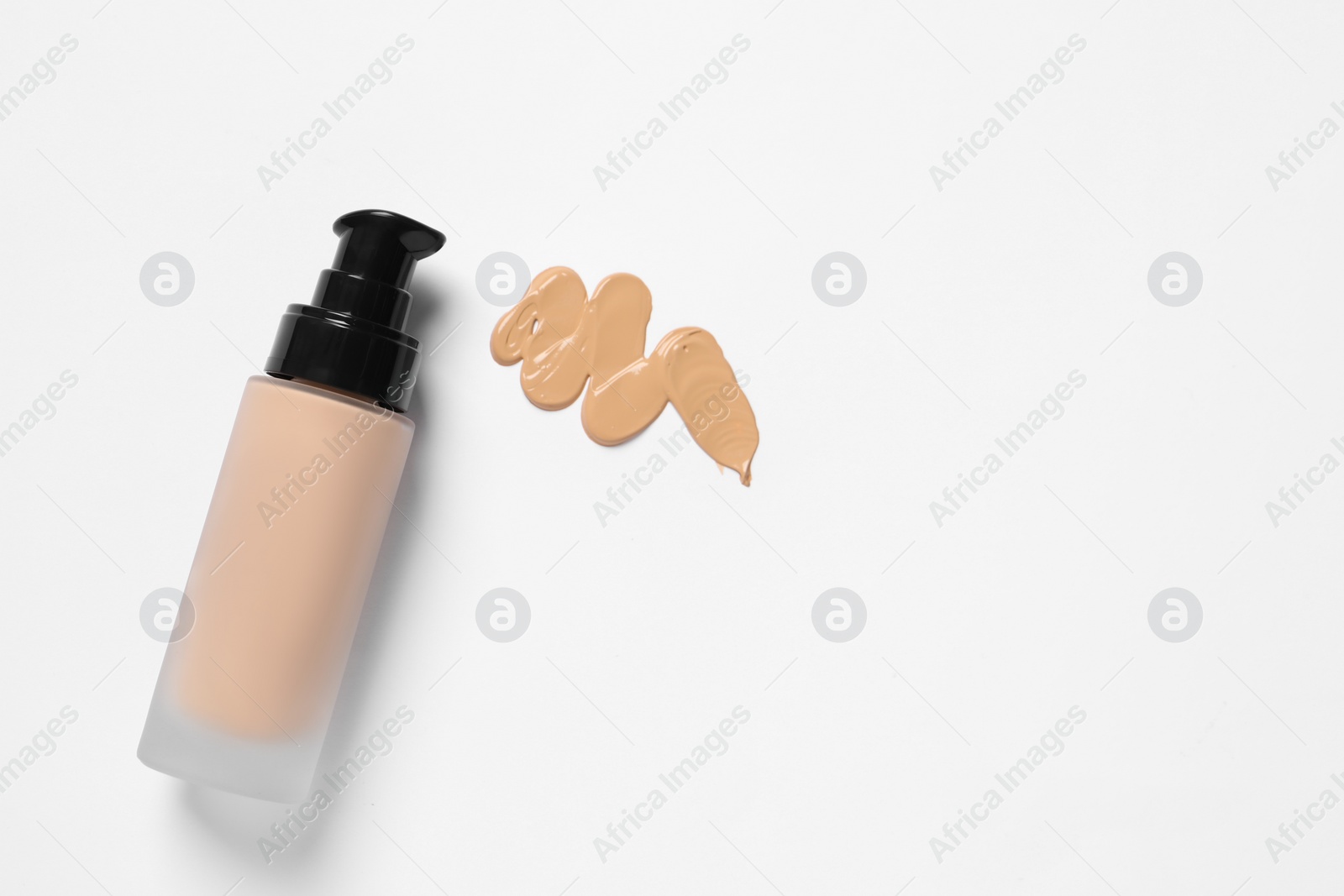 Photo of Liquid foundation and swatch on white background, top view. Space for text
