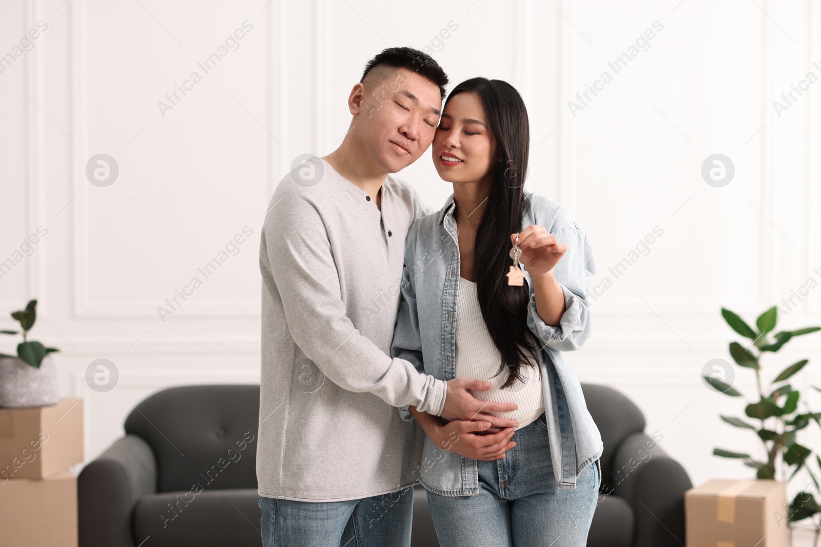 Photo of Pregnant woman and her husband with key in their new apartment