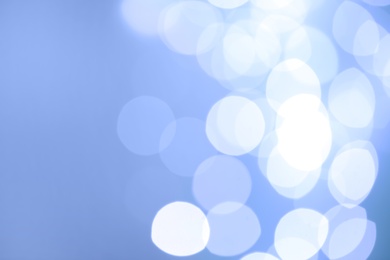 Blurred view of beautiful lights on light blue background, space for text