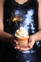 Woman holding birthday cupcake with sparkler, closeup