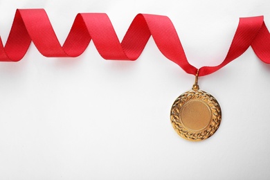 Photo of Gold medal on white background, top view with space for text. Symbol of victory