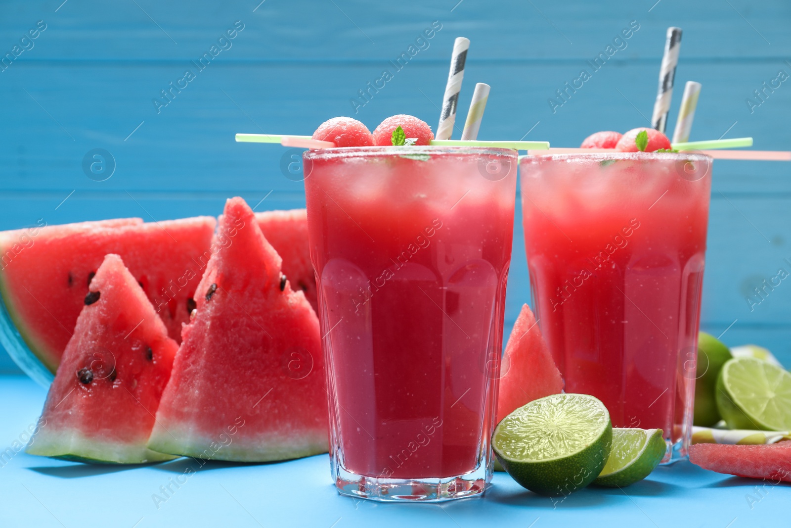 Photo of Tasty watermelon drink and fresh fruits on light blue background