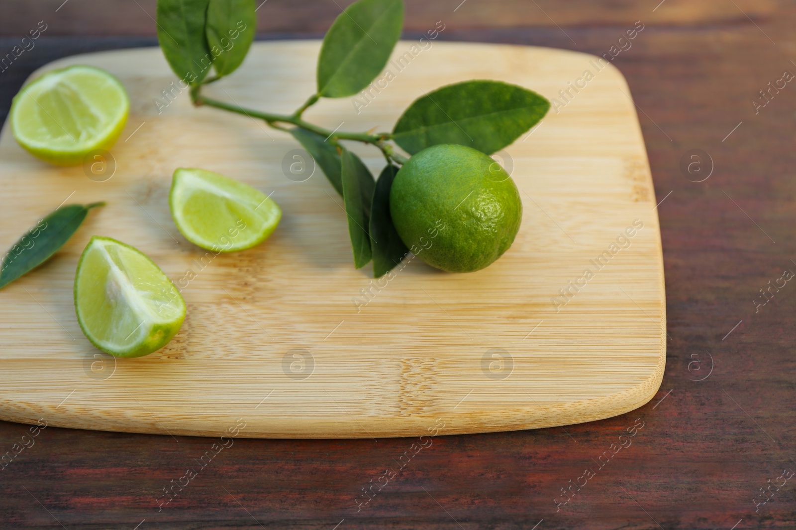 Photo of Fresh limes and leaves on wooden table, closeup