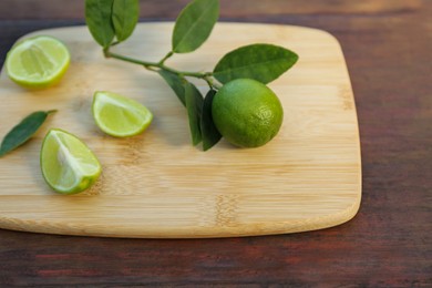 Fresh limes and leaves on wooden table, closeup