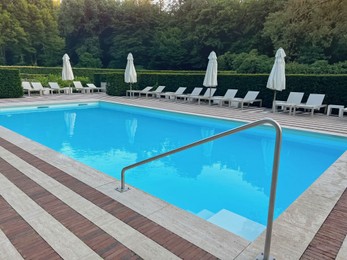 Photo of Outdoor swimming pool in luxury hotel on sunny summer day. Time for relax