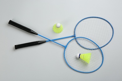 Photo of Rackets and shuttlecocks on light grey background, flat lay. Badminton equipment