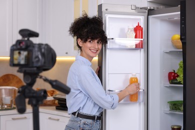 Photo of Smiling food blogger explaining something while recording video in kitchen