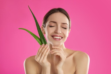 Photo of Happy young woman with aloe leaves on pink background