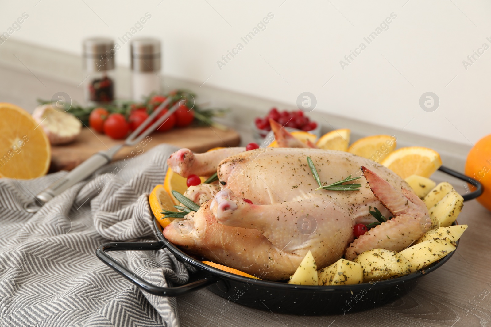 Photo of Chicken with orange and potato slices in baking pan on wooden table