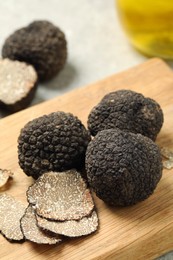 Whole and cut black truffles on wooden board
