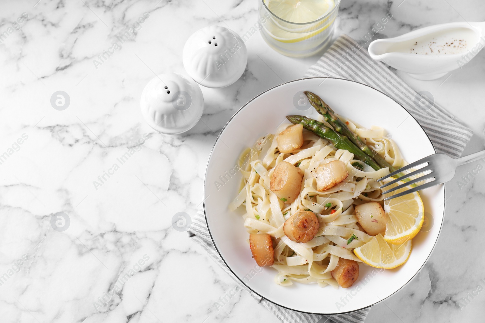 Photo of Delicious scallop pasta served on white marble table, flat lay. Space for text