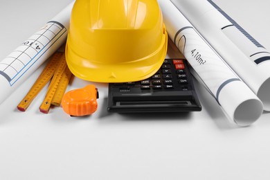 Photo of Construction drawings, safety hat, calculator, tape measure and folding ruler on white background