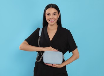 Photo of Beautiful young woman with stylish bag on light blue background