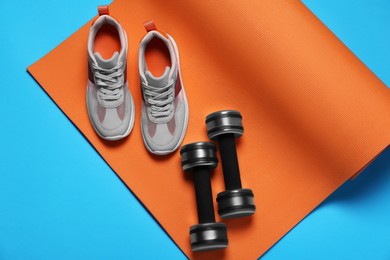 Photo of Exercise mat, dumbbells and shoes on turquoise background, flat lay
