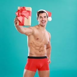 Photo of Sexy shirtless Santa Claus with gift on blue background
